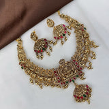 Gold necklace with red and green gemstones on a white surface