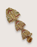 Decorative gold earring with red and green gemstones on a light gray background