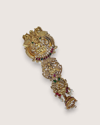 Decorative gold brooch with gemstones on a light beige background