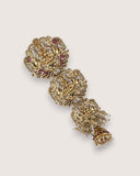 Gold ornate earring on a light gray background