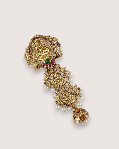 Gold earring with gemstones on a beige background