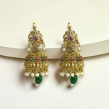 Ornate gold earrings with green and red gemstones on a white background
