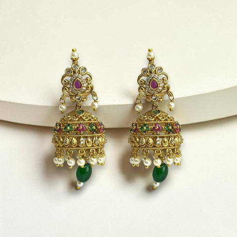 Ornate gold earrings with green and red gemstones on a white background