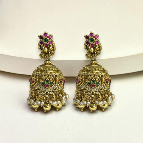 Ornate gold earrings with gemstones on a white background