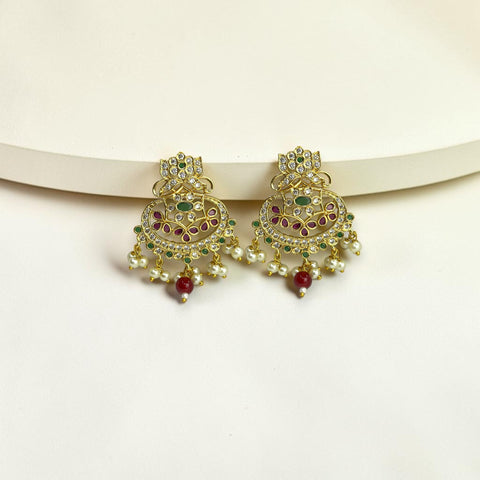 Gold earrings with green and red stones on a white background