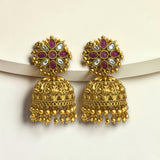 Gold earrings with red and white stones on a beige background