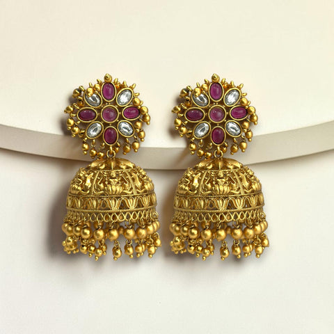 Gold earrings with red and white stones on a beige background