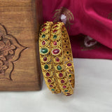 Gold bangles with gemstones on a wooden surface