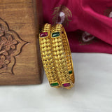 Gold bangles with gemstones on a wooden surface
