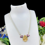 Pearl necklace with a gold pendant on a mannequin bust against a floral background