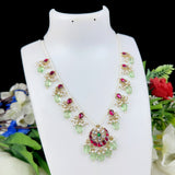 Decorative necklace with green and red stones on a white mannequin bust with floral background