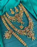 Ornate gold jewelry set with colorful stones on a teal fabric background