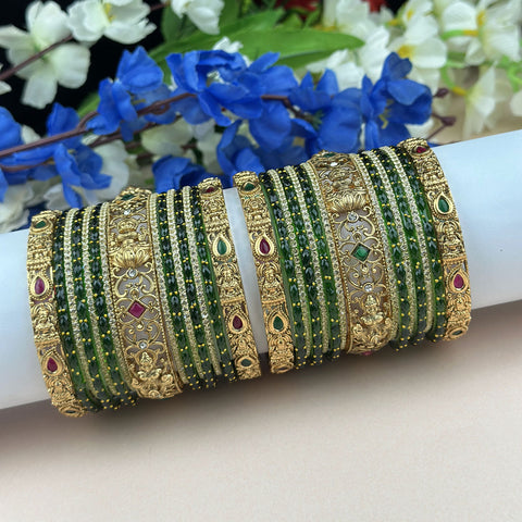 Decorative bangles with green stones and gold accents on a white arm against a floral background.