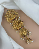 Gold bracelet with intricate design and pearls on a white fabric background