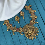 Ornate gold necklace and earrings on a blue fabric background