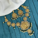 Gold and green jewelry set on a blue surface