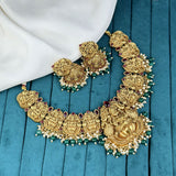 Gold necklace with intricate designs on a blue fabric background