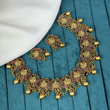 Ornate gold necklace and earrings on a blue fabric background