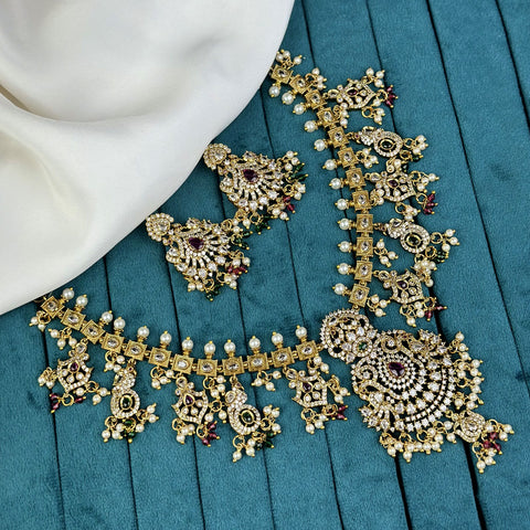 Ornate gold and pearl jewelry set on a teal surface
