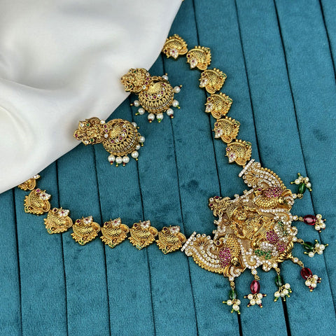 Gold necklace with intricate designs on a teal fabric background