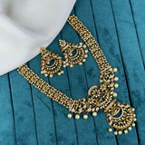 Ornate gold necklace with pearls and gemstones on a teal fabric background