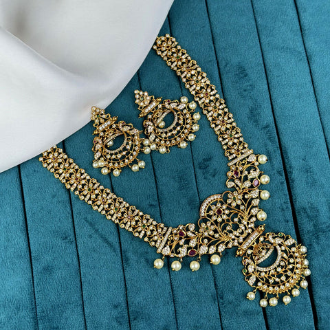 Ornate gold necklace with pearls and gemstones on a teal fabric background