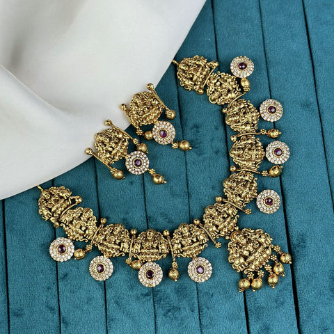 Gold necklace and earrings on a blue fabric background