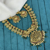 Ornate gold necklace with red and green stones on a teal fabric background