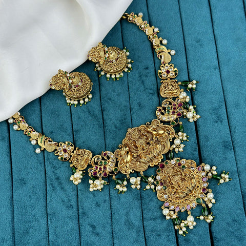 Ornate gold necklace with intricate designs on a blue fabric background