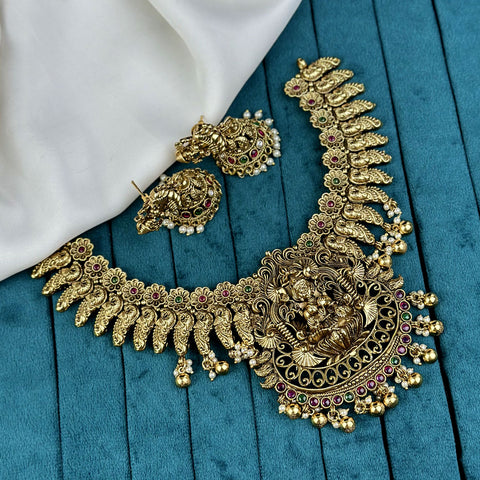 Ornate gold necklace with gemstones on a blue fabric background