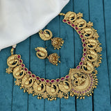 Gold necklace with red gemstones and matching earrings on a blue fabric background