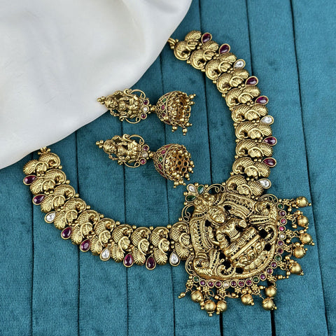 Gold necklace and earrings with gemstones on a blue fabric background