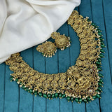 Ornate gold necklace with green beads on a blue surface