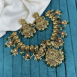 Ornate gold necklace with green beads on a blue fabric background