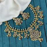 Ornate gold necklace and earrings on a blue fabric background
