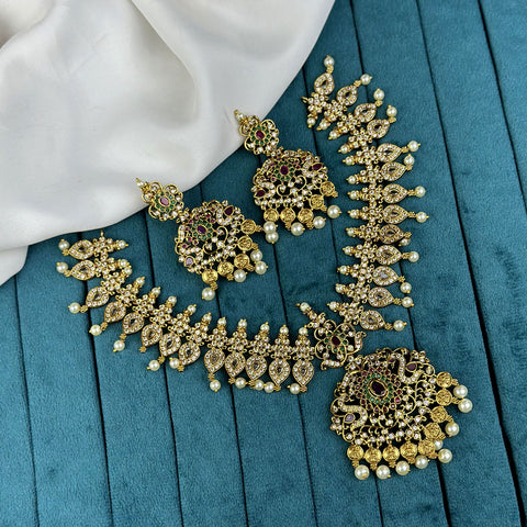 Ornate gold necklace and earrings on a blue fabric background