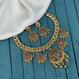 Ornate gold necklace with red and green gemstones on a blue fabric background