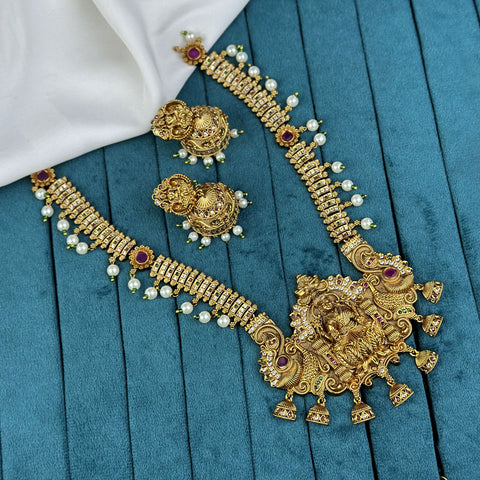 Gold necklace and earrings set on a blue fabric background