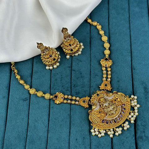 Gold necklace and earrings on a blue fabric background