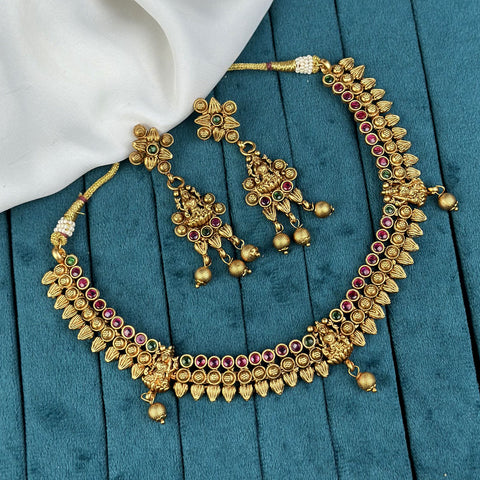 Gold necklace and earrings set on a blue fabric background