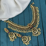 Gold necklace with red gemstones on a teal fabric background