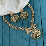 Ornate gold necklace and earrings on a teal fabric background