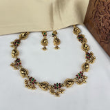 Gold necklace and earrings set on a white surface with a wooden box in the background
