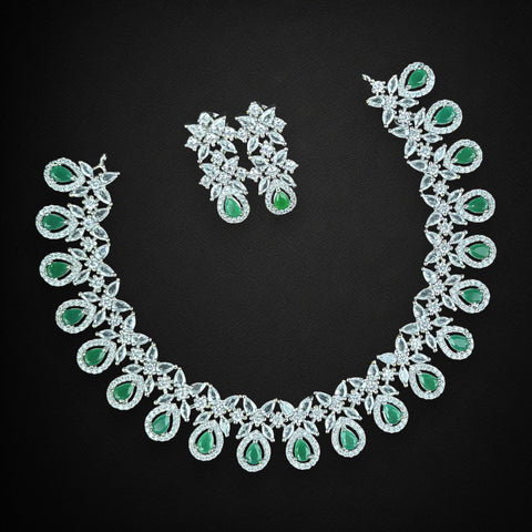 Jewelry set with necklace and earrings featuring green gemstones on a black background