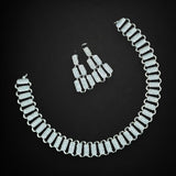 Silver necklace and earrings on a black background