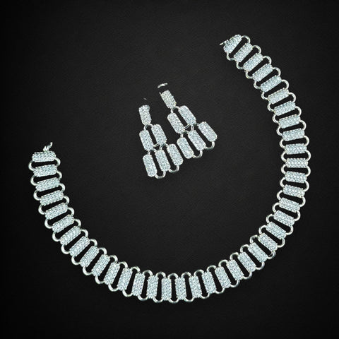 Silver necklace and earrings on a black background