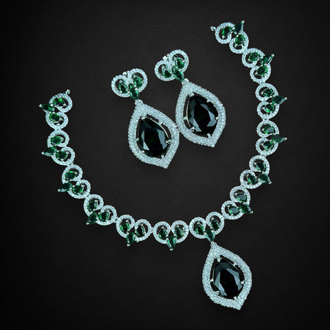 Jewelry set with necklace and earrings featuring green gemstones on a black background