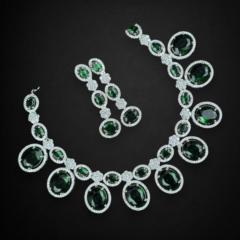 Jewelry set with necklace and earrings featuring green gemstones on a black background