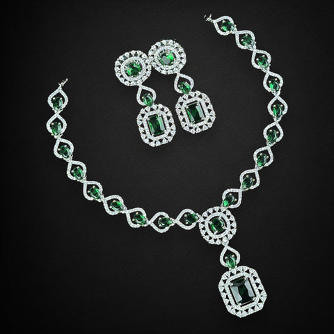 Jewelry set with necklace and earrings featuring green gemstones on a black background