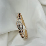 Rose gold bracelet with diamond accents on a white fabric background